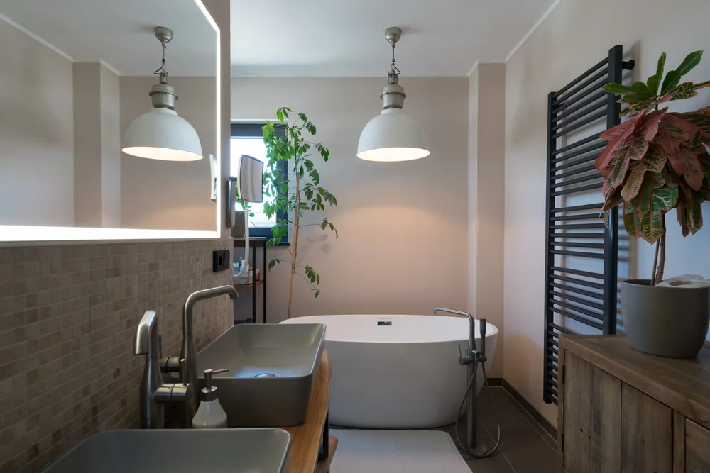 Badezimmer als einzelne Aufnahme: das Fenster ist ausgebrannt, die Pendelleuchten färben den Raum warm ein