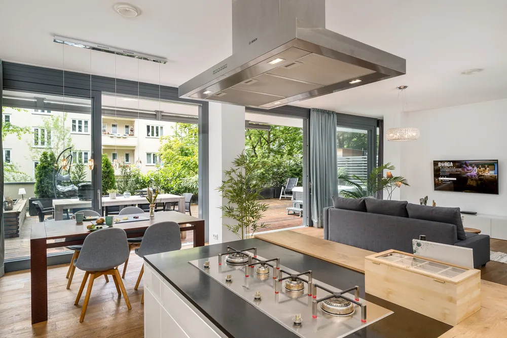 Küche mit Kochinsel und großer Fensterfront, mit Flambient-Technik fotografiert: Raum hell, Blick nach draußen klar