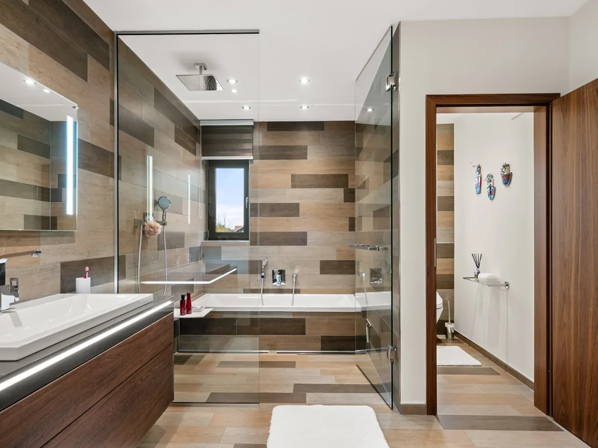 Badezimmer in Holzoptik mit Dusche und indirekter Beleuchtung.
