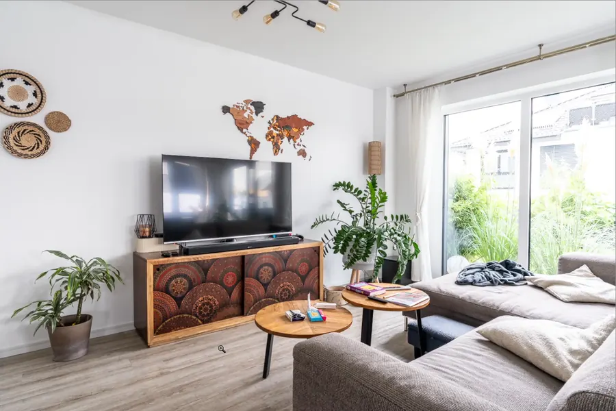 Unaufgeräumtes Wohnzimmer mit Decke und Kleinkram auf dem Tisch.